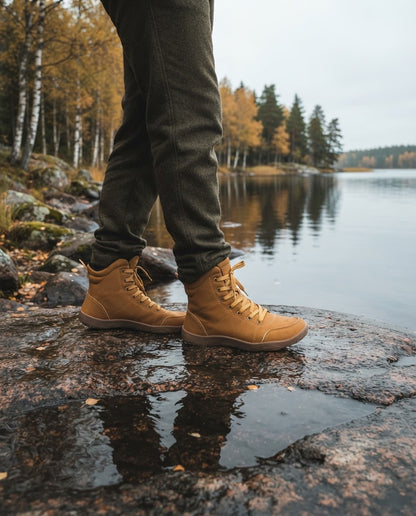 Person i Canyon Barefoot Boots vid en svensk sjöstrand med granitklippor och höstskog